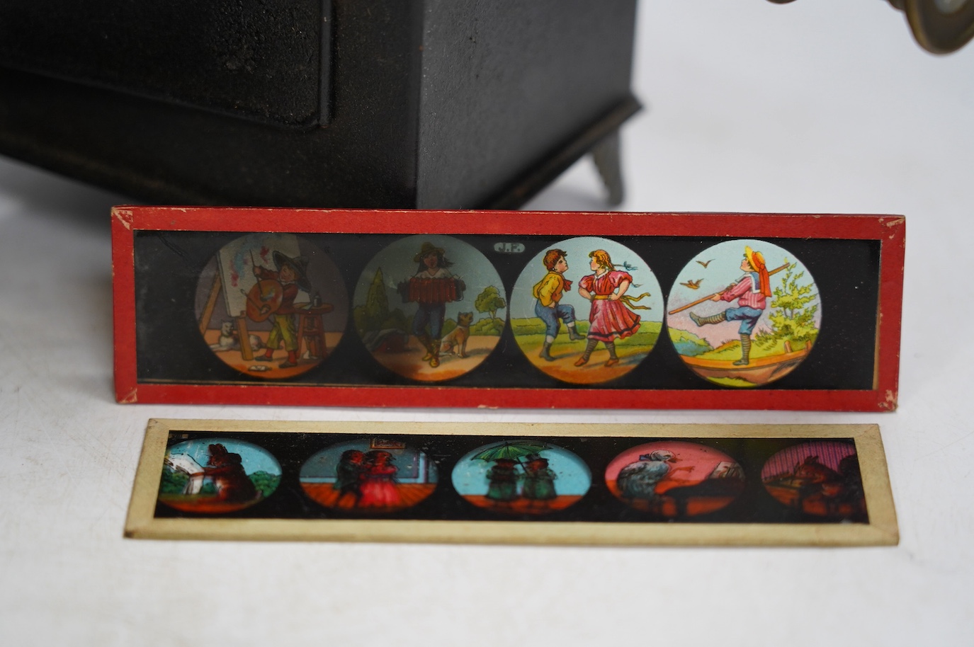 A late 19th century child's tinplate magic lantern with a selection of German slides, magic lantern 21cm high. Condition - fair to good